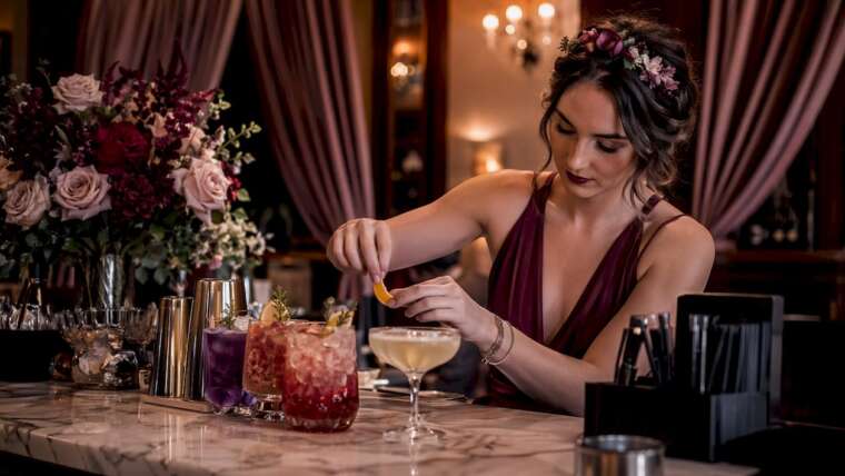 Bartender arranging colorful craft cocktails at wedding bar