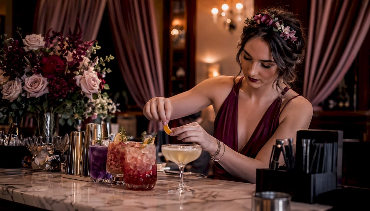 Bartender arranging colorful craft cocktails at wedding bar
