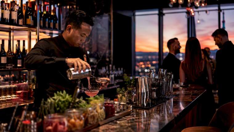 Bartender mixing cocktails at illuminated beverage station