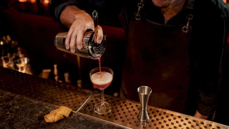 Mixologist pouring cocktail at luxury bar