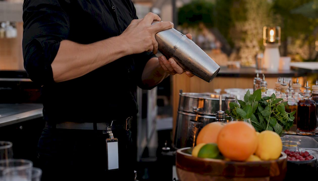 Bartender shaking cocktail with TAM card visible
