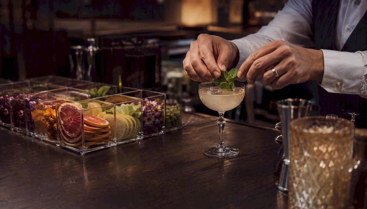 Bartender adding fresh herb garnish at mocktail station
