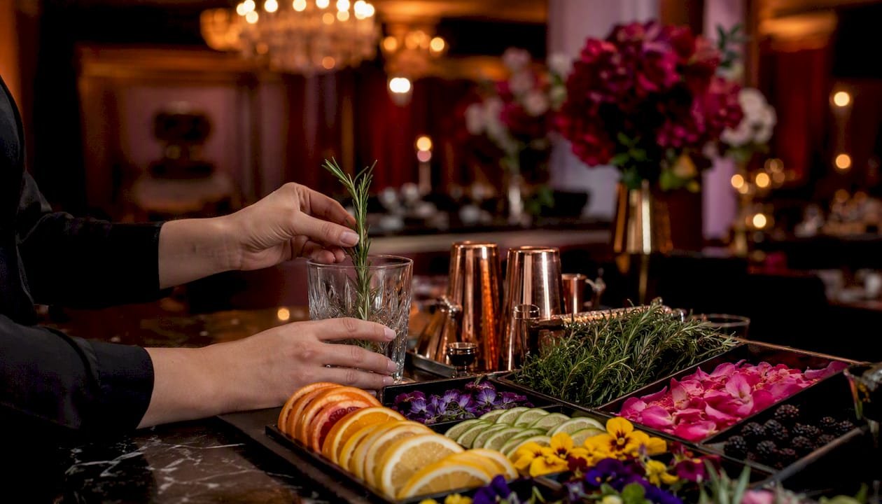 Hands adding garnish to cocktail at station