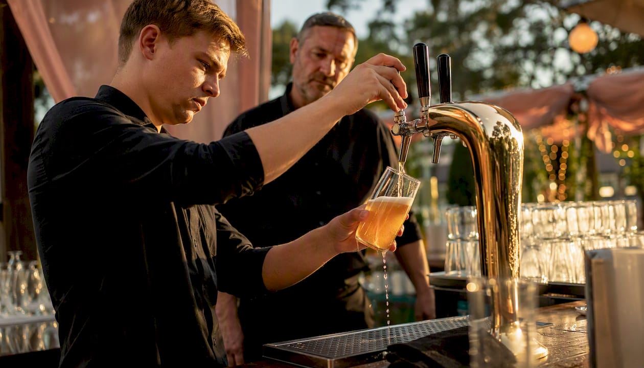 Young bartender pouring beer under supervision