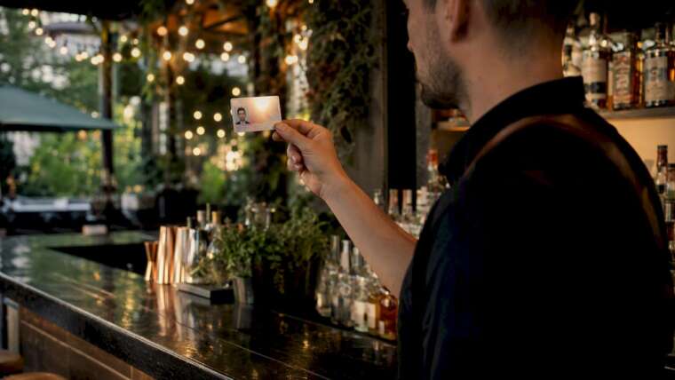 Bartender checking ID card at bar