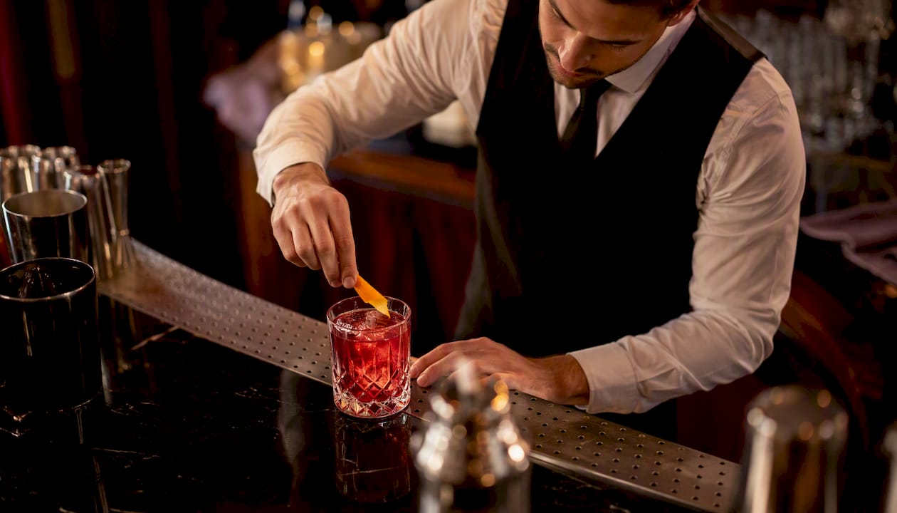 Bartender pouring signature cocktail with garnish
