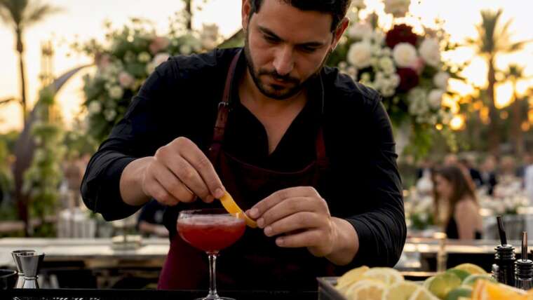 Bartender preparing signature cocktail at wedding bar