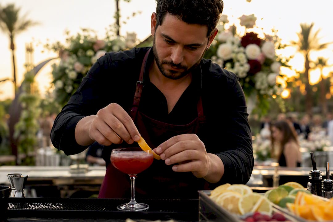 Bartender preparing signature cocktail at wedding bar