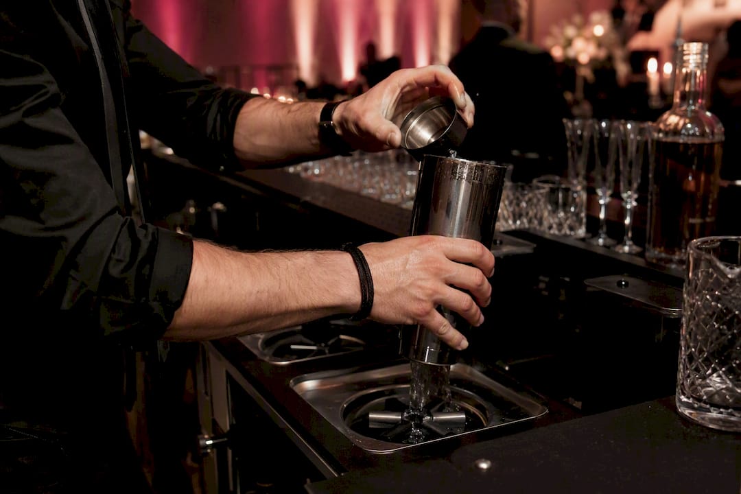 Bartender rinsing shaker at custom bar