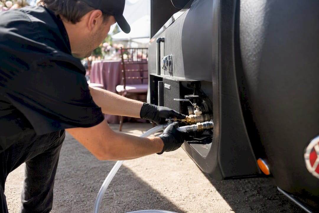 Hands connecting water hoses on mobile bar