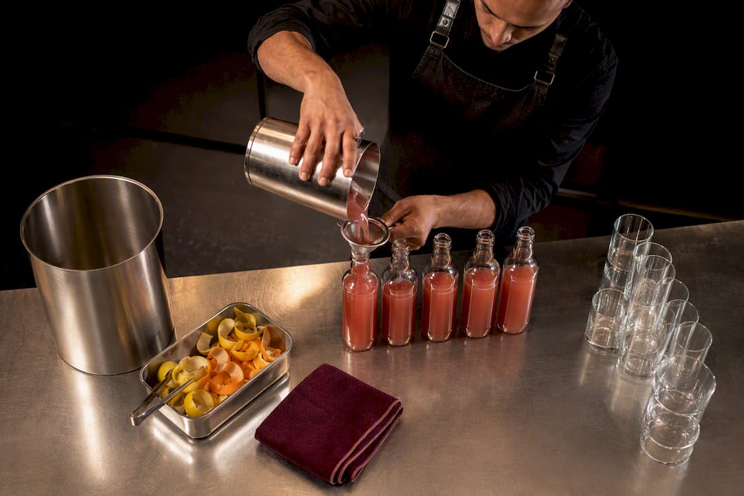 Bartender batching cocktails for event service