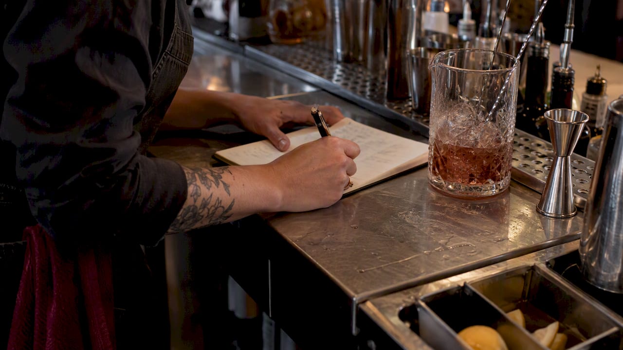 Bartender recording cocktail recipe test notes