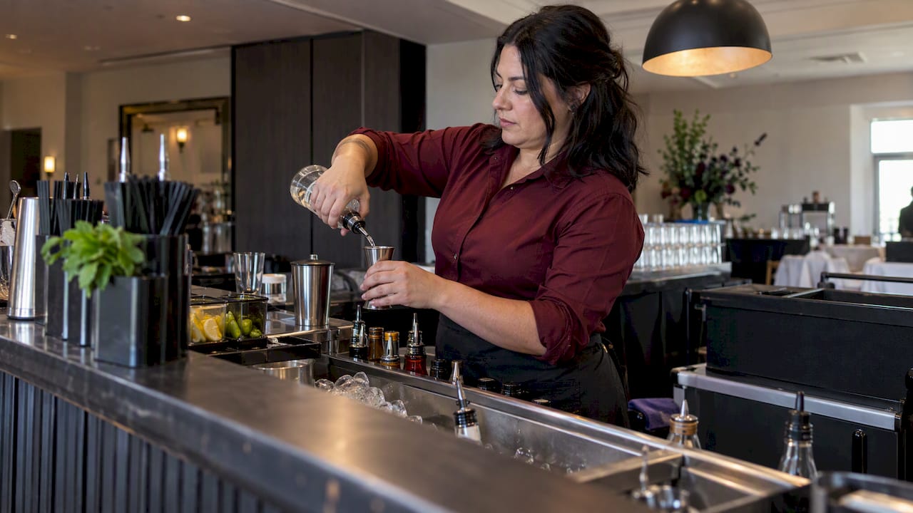 Bartender pouring beside clear bar workspace